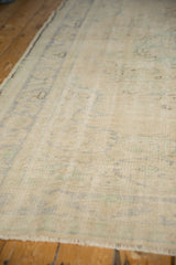Faded ivory and blue tones in the distressed, low pile of a vintage Oushak.