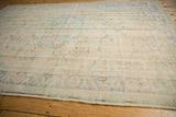Distressed vintage Oushak rug side, showing faded blue-green border and secured selvage.