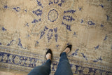 Distressed vintage Oushak carpet with ivory field, faded cobalt blue patterns, and border.