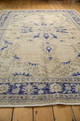 Distressed Oushak carpet showing worn ivory pile with cobalt blue and pale coffee motifs.