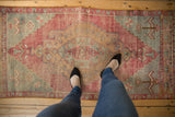 Faded cochineal red Oushak runner, deep gold and slate blue palette, showing even wear.