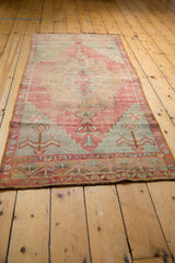 Vintage distressed Oushak runner with faded red, blue medallion, and pinwheel starburst.