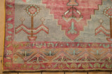 Textured distressed Oushak rug corner, faded cochineal red and slate blue designs.