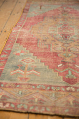 Distressed Oushak rug runner showing faded red and blue geometric pattern, yellow selvage.