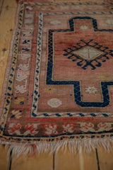 Vintage distressed Anatolian rug corner, showing worn dusty rose pile and navy geometric detail.