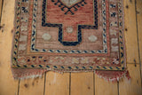 Distressed end of a vintage Anatolian rug showing terracotta, navy, and beige border.