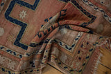 Folded vintage Anatolian rug with distressed texture, faded rose field, navy hook motif, and wear.