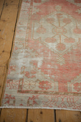 Distressed Oushak rug runner with faded red pattern, ivory field, and visible foundation.
