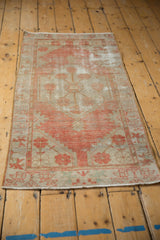 Distressed vintage Oushak rug corner showing faded terracotta motifs, worn pile, and secured end.
