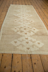 Textured pile of a distressed Oushak runner, showing ivory and beige geometric motifs.