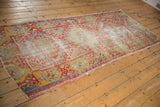 Distressed vintage Oushak runner showing worn pile, geometric motifs in red, blue, yellow.