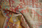 Folded vintage distressed Oushak runner displaying textured pile and colorful geometric motifs.