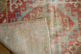 Vintage distressed Oushak rug: worn red, blue geometric pile and visible hand-knotted foundation.