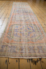 Distressed vintage Oushak runner with faded terracotta, blue, green motifs and worn texture.