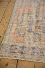 Distressed Oushak rug's worn pile texture, visible foundation, in faded terracotta, blue, mint.
