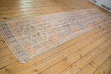Distressed vintage Oushak runner showing worn pile, faded terracotta, blue, and mint green patterns.