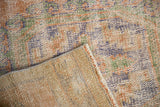 Close-up of distressed hand knotted Oushak runner: worn pile, exposed foundation, side selvage.