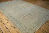 Faded apricot and ocean green hues on a distressed Oushak carpet with even wear.
