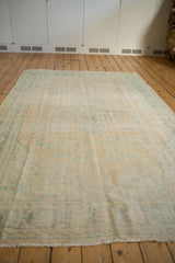 Distressed vintage Oushak carpet end with faded ocean green border and visible wear.