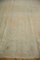 Vintage distressed Oushak rug pile with faded apricot and ocean green pattern, foundation visible.