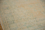 Distressed Oushak rug pile with apricot and ocean green tones, showing wear and fringe.