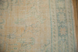Distressed vintage Oushak carpet detail, faded apricot and ocean green vinery with textured wear.