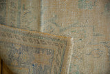 Texture detail of the distressed Oushak rug, showing faded apricot, ivory, and ocean green.
