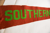 Detailed view of hand-sewn green letters on antique red felt flag with small holes.