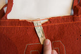 Green Mountain Studios tag on antique reddish-brown felt flag, showing aged texture and loss.