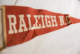 Vintage red felt flag with white 'RALEIGH N.C.' lettering and gentle creasing.