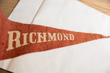 Textured reddish-orange felt of the vintage Richmond flag, featuring beige lettering.