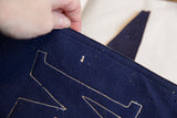 Antique Mercersburg felt flag detail: blue fabric, cream letter stitching, and a moth nibble.