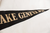 Close-up of vintage black felt Lake Geneva flag showing 'GENEVA, WIS.' text in tan.