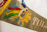 Native American figure with yellow-orange face and real vibrant feathers on vintage Tulsa flag.