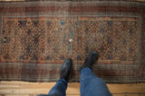 Antique Belouch rug showcasing geometric field, visible hard wear, tatters, and repairs.