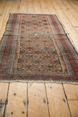 Antique Belouch rug with repeating pawn motif, rich patina, and visible storied repairs.