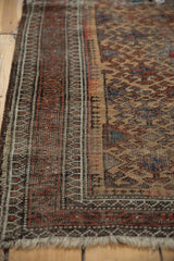 Antique Belouch rug's geometric border in chocolate, madder, and ivory, highlighting edge wear.
