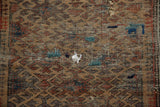 Antique Belouch rug with hard wear, tatters, holes, and colorful scattered repairs.