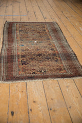 Detail of antique Belouch rug with worn pawn motif border and repeating guls.