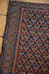 Tattered side edge of vintage Afshar rug with mend, navy blue field, and serpent border.