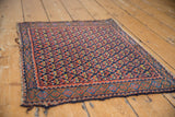 Afshar rug corner detail showing unusual serpent motif border, navy, madder, and tattered side.