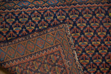 Hand-knotted Afshar rug detail: navy blue floral field meeting madder root serpent border.