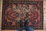 Vintage Lilihan rug detail showing pale raspberry red field, cobalt blue palmettes, and worn pile.