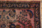 Vintage Lilihan rug corner: worn pale raspberry field, cobalt blue leaves, navy floral border.
