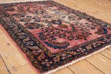Vintage Lilihan rug corner detail: worn raspberry field, serrated leaves, navy blue floral border.