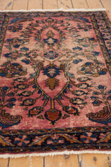 Navy blue meandering floral border and worn raspberry field of a vintage Lilihan rug.