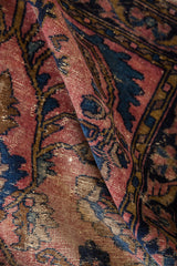 Aged hand-knotted pile of Lilihan rug, with faded raspberry red and cobalt blue motifs.