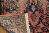 Folded vintage Lilihan rug displaying worn raspberry red field and intricate floral border.