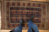 Antique Belouch rug showcasing rich chestnut, navy, and madder root patterns underfoot.