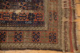 Antique Belouch rug, stylized chestnut, madder, navy patterns, threadbare pile, tattered fringe.